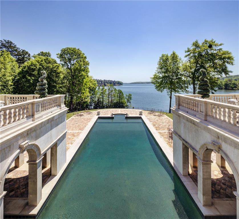 Long limestone pool at LONGVIEW flanked by twin balustraded terraces, framed by mature trees, opening directly onto Lake Oliver's blue water and far shore